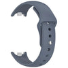 A gray silicone replacement strap for a fitness tracker, shown in a curved form.