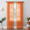 Orange sheer curtains with pom pom detailing and 3D jacquard rod pockets hanging in a window.