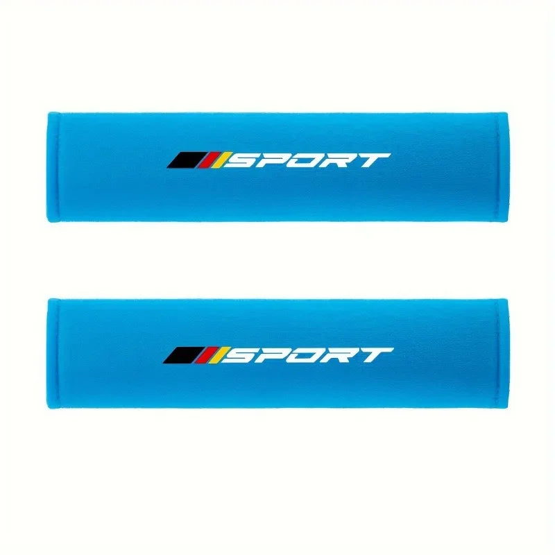 A pair of bright blue soft car seat belt cushions with white and black Sport branding.