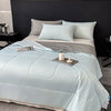 Light blue arc-chill cooling blanket with white pillows on a bed.