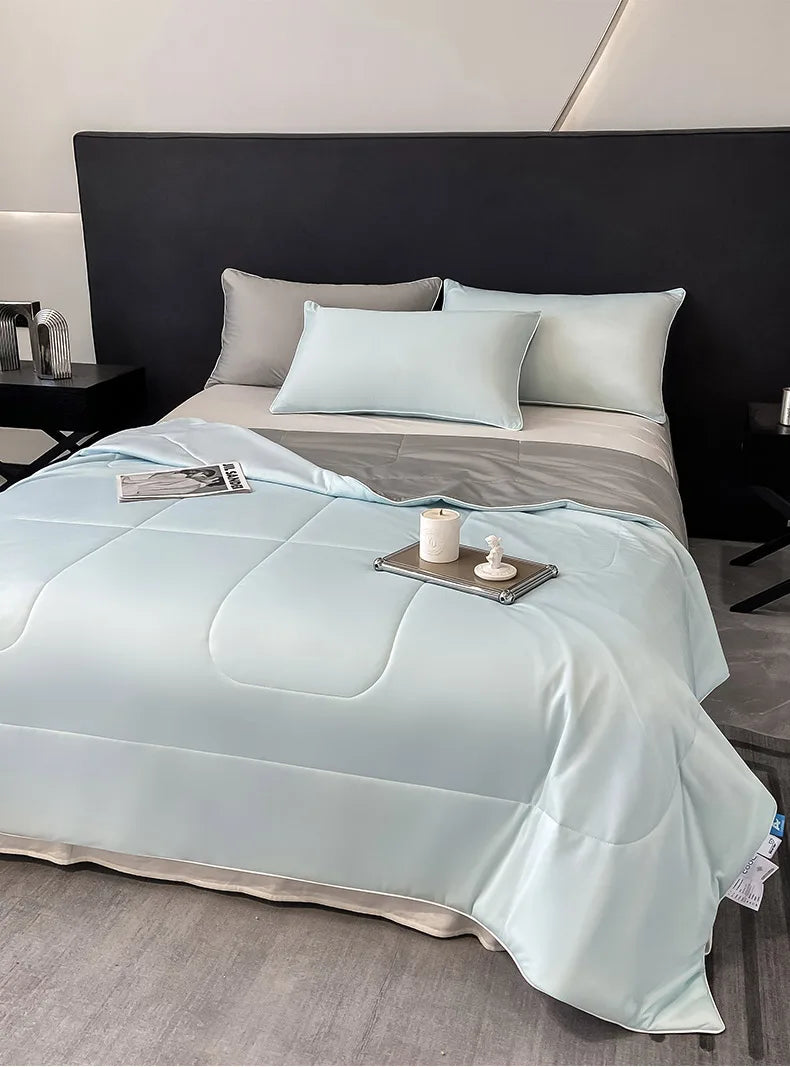 Light blue arc-chill cooling blanket with white pillows on a bed.