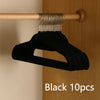 Black velvet non-slip hangers with metal hooks hanging from a wooden rod.