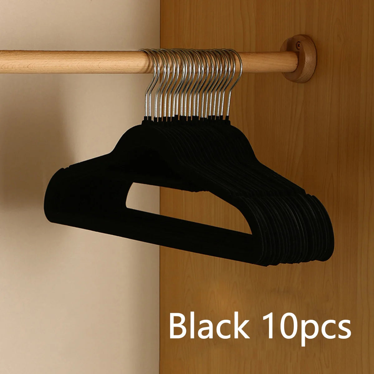 Black velvet non-slip hangers with metal hooks hanging from a wooden rod.