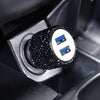 Close-up of a black rhinestone dual USB car charger with blue accents inside a device slot.