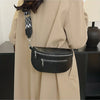 A black multi-pocket PU leather waist bag with an adjustable strap is shown hanging from a beige coat.