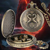 A silver dragon-themed pocket watch dice case is shown open, revealing seven metal polyhedral dice and a pendant.