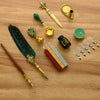 A vintage calligraphy fountain pen set with a gold nib, wax seal stamp kit, and various related tools on a wooden surface.