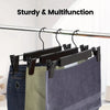 Black adjustable clip hangers holding denim and fabric garments on a rod.