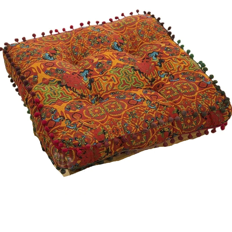 An orange and red bohemian cotton linen floor cushion with decorative fringe.