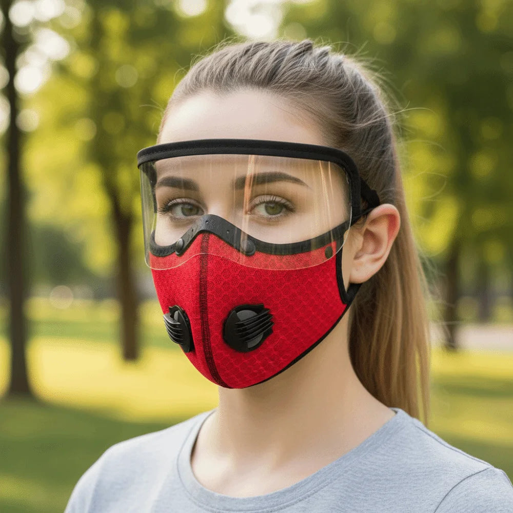 A woman wearing a red reusable cycling face mask with a clear shield over her face outdoors.