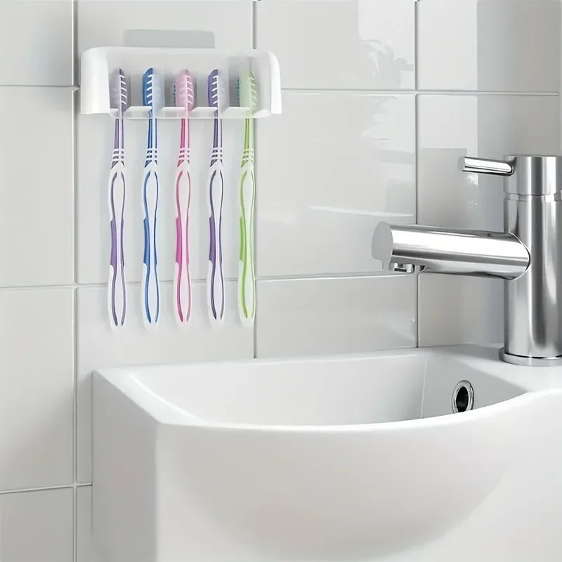 Weißer selbstklebender Zahnbürstenhalter mit bunten Zahnbürsten, montiert an einer Fliesenwand über einem Waschbecken.