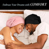 A smiling couple wearing silk satin sleep bonnets while relaxing in bed.