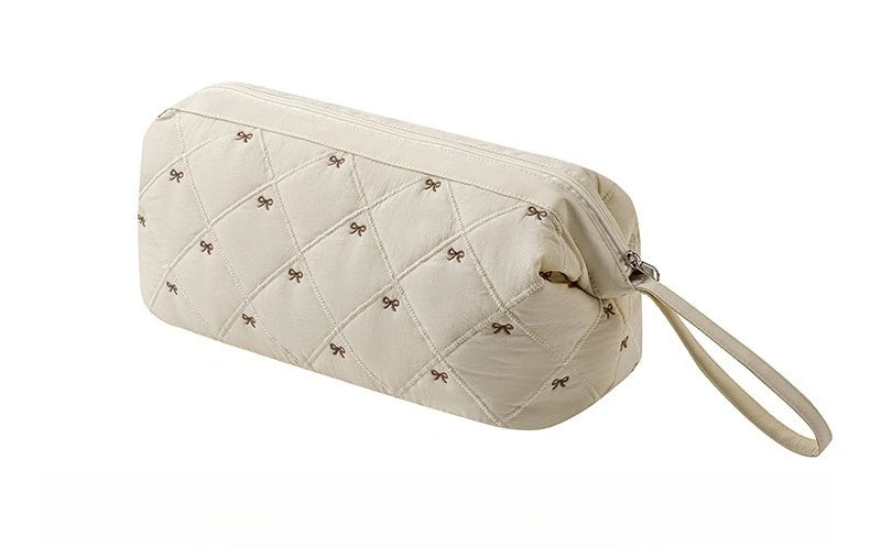 A beige quilted storage bag for a portable hair dryer and styling tool with a fabric strap.