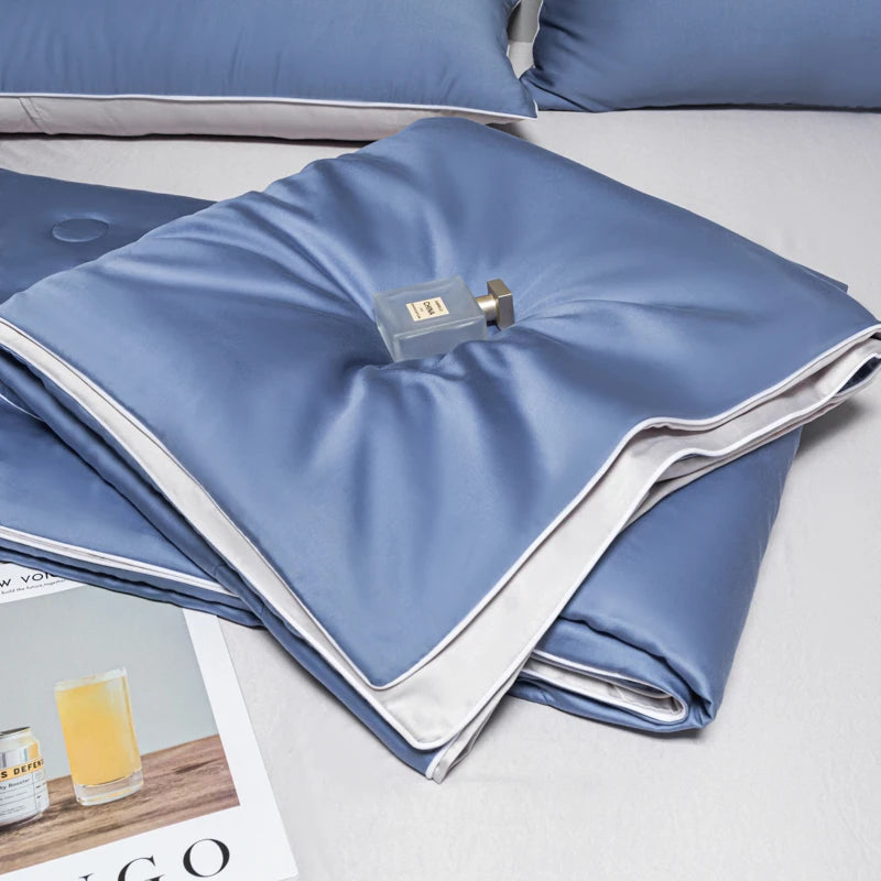 Light blue ice silk quilt folded on a bed, showing the fabric texture and a silver zipper.