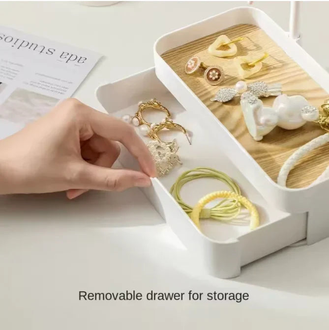 A white jewelry display rack with a removable drawer and wooden base, showing various gold and pearl jewelry pieces.