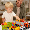 A boy is playing with a diecast metal fruit and vegetable transport truck model and various accessories.