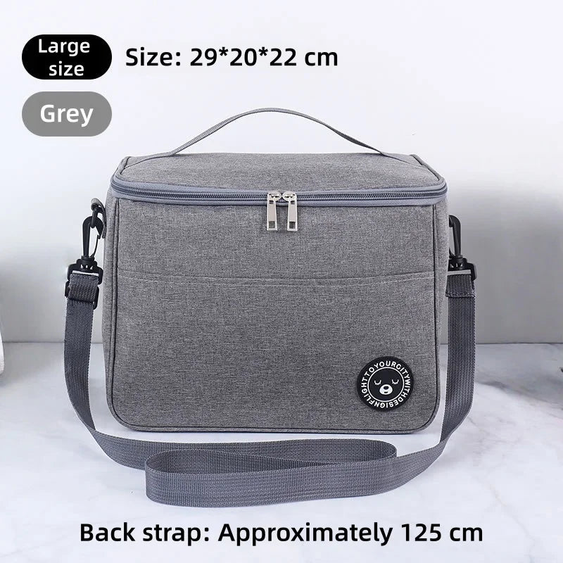 A grey thermal insulated lunch bag with a black adjustable shoulder strap is shown on a white surface.