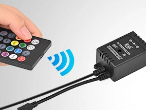 A hand holds a remote control connected by wires to a black LED music car interior light kit controller.