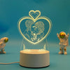 A clear acrylic heart-shaped LED night light lamp featuring a silhouette of two embracing figures.