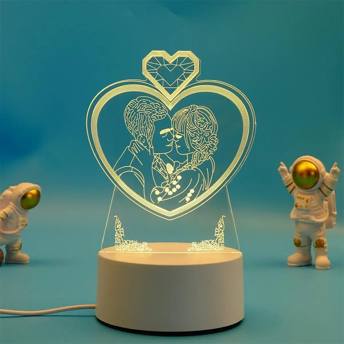 A clear acrylic heart-shaped LED night light lamp featuring a silhouette of two embracing figures.