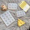 A collection of silicone paint palette trays in white and yellow on a gray fluffy surface.