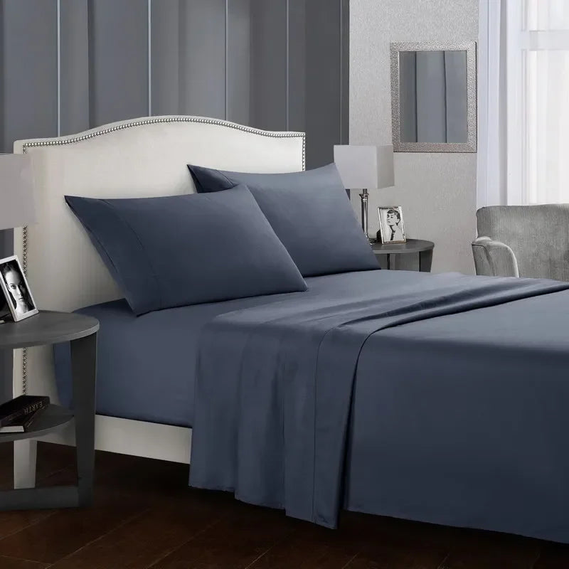 A bedroom featuring a white headboard and blue bedding set with a gray wall and wooden floor.