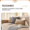 A beige sofa is shown with a gray non-slip cover and decorative pillows in a bright living room setting.
