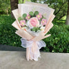 Bouquet aus handgefertigten Häkelblumen in rosa und weiß, umwickelt mit durchscheinendem Band und präsentiert in einem hellro