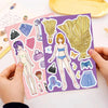 A hand holds a sheet of purple stickers featuring princess costume elements like bags, flowers, and clothing pieces.