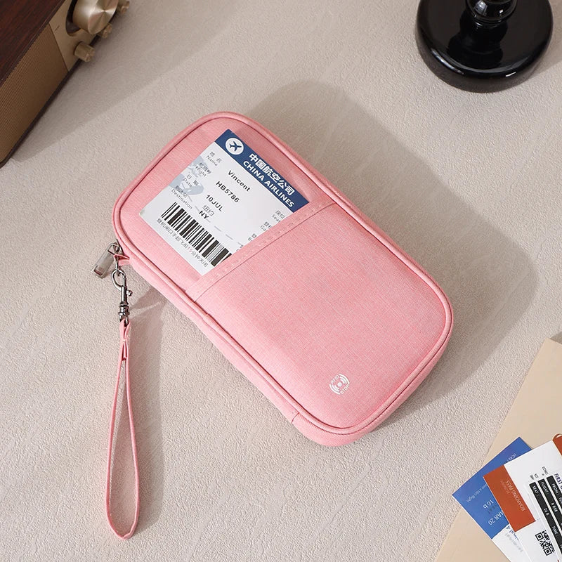 Pink RFID-blocking passport holder with a strap, placed on a light surface.