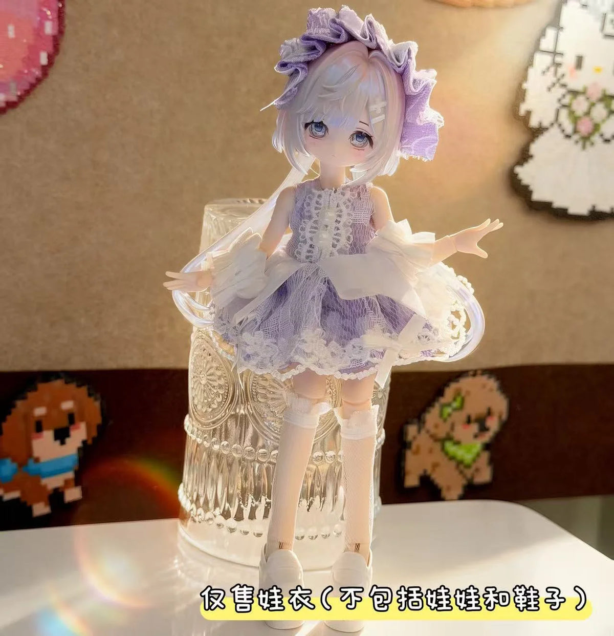 A white and lavender BJD doll wearing a frilly dress outfit, displayed in a glass container.