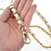 A hand holds a gold-tone chain strap with white accents, featuring a lobster clasp, for bags and phone cases.