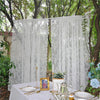 Two panels of sheer floral lace curtains hanging outdoors on a table setting.