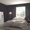 A bedroom featuring a large window and a bed with white linens against a dark gray textured wall.