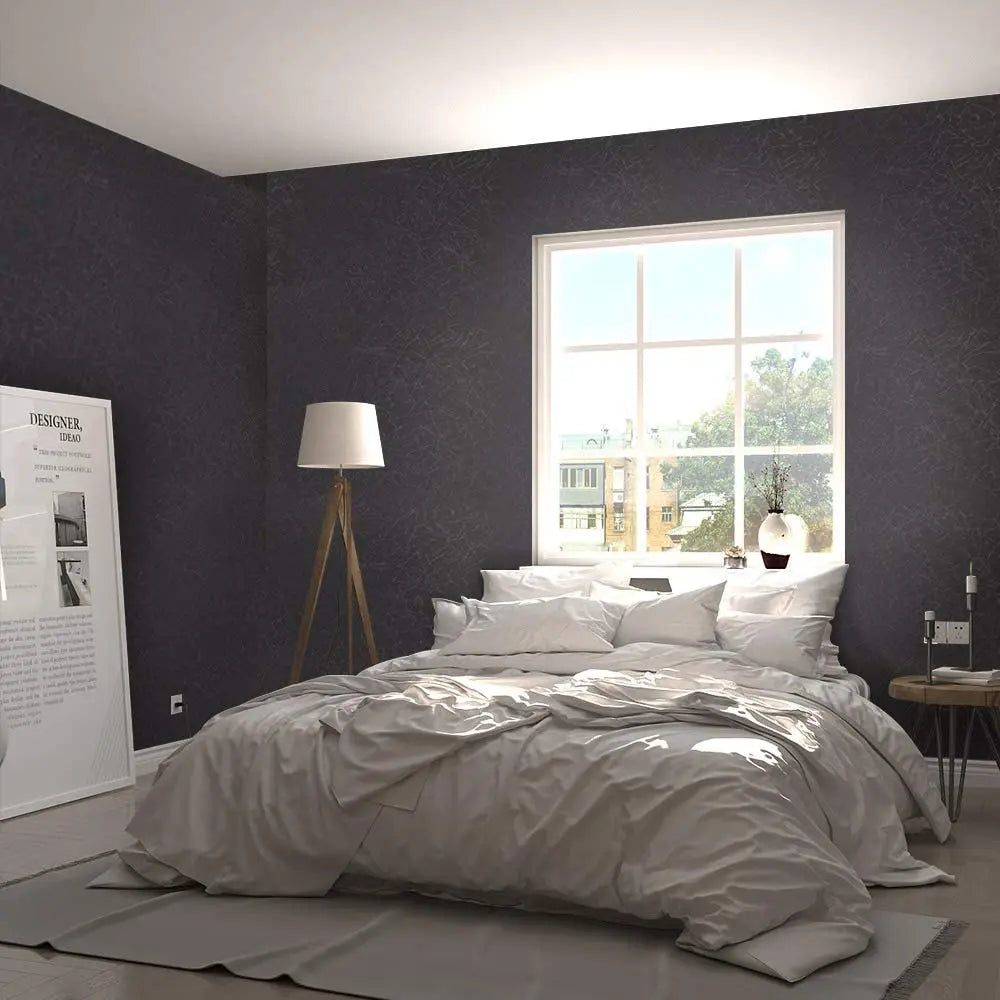 A bedroom featuring a large window and a bed with white linens against a dark gray textured wall.