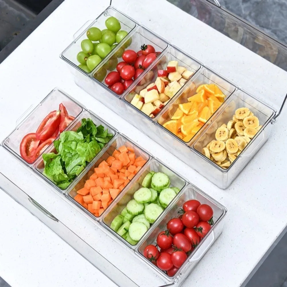 A silver chilled condiment server holds various fresh vegetables like tomatoes, cucumbers, and peppers in separate compartmen