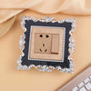 A decorative switch cover frame with a rose pattern border and a brass-toned electrical outlet plate.