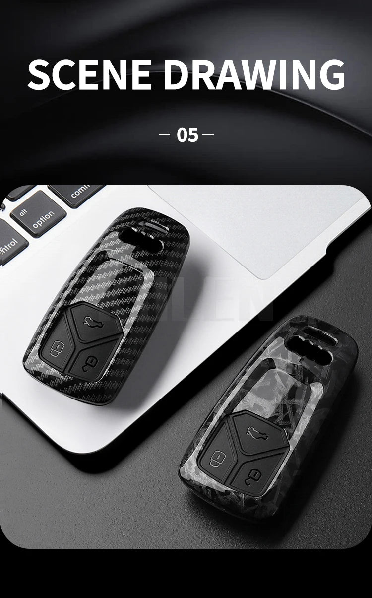 A close-up of a black carbon fiber style key fob cover resting on a white laptop surface.