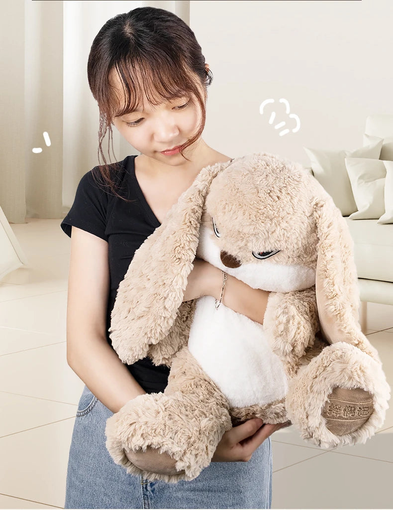 A woman is holding a light brown long-eared rabbit plush toy against her chest.
