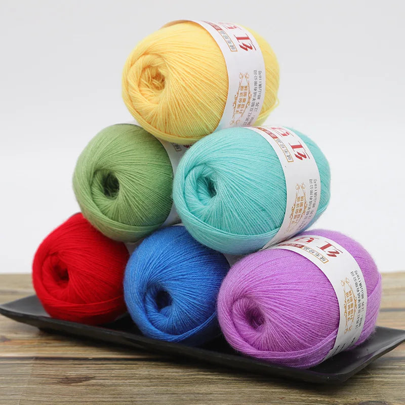 A collection of colorful fine yarn balls in various shades including yellow, green, red, blue, and purple arranged on a dark 