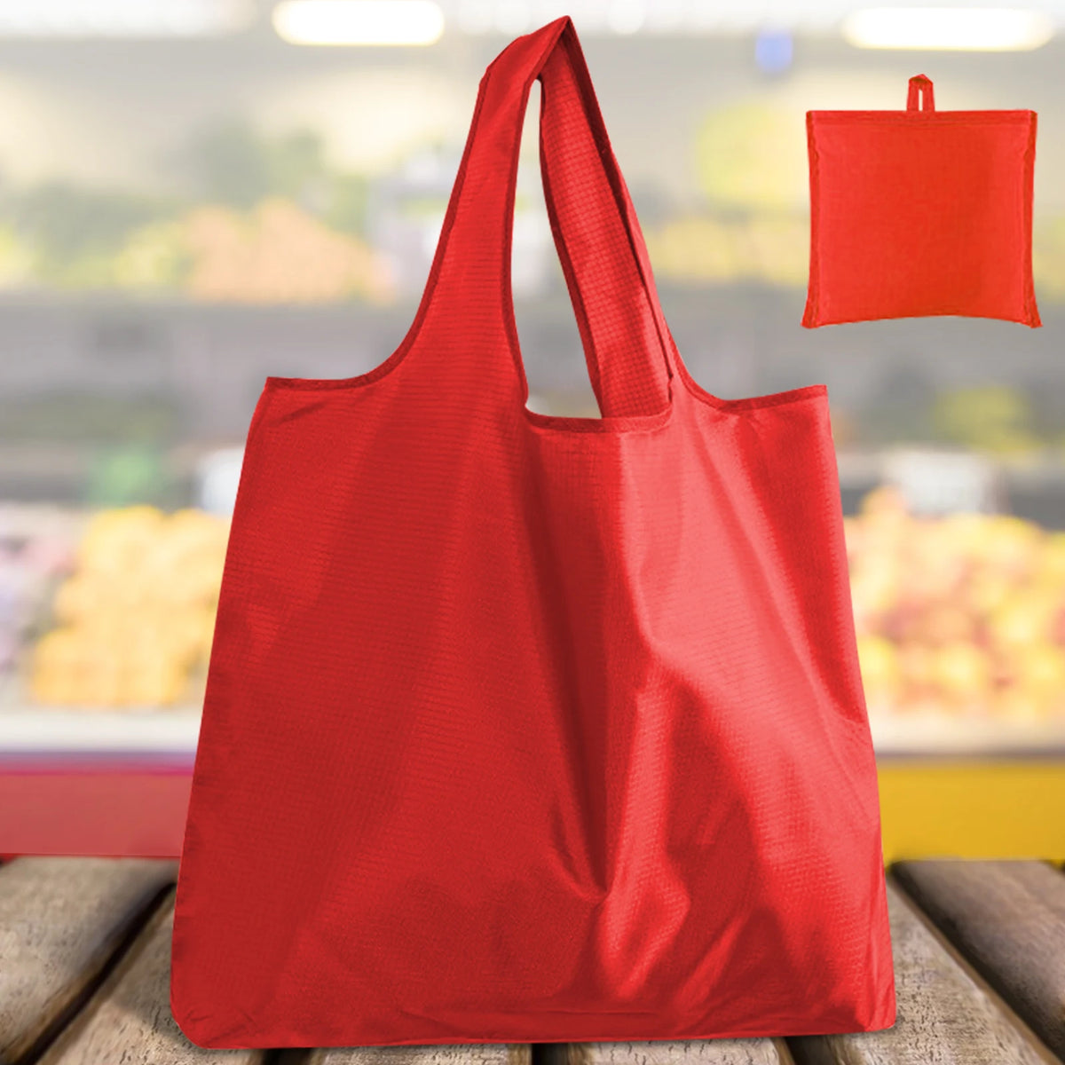 A bright red reusable grocery bag is shown in a full view, with another folded bag visible in the background.