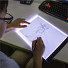 A person is using a transparent LED tracing light to draw on paper with a pen.