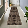 A long runner rug with vintage tribal geometric patterns in brown and beige tones placed on a light tile floor.