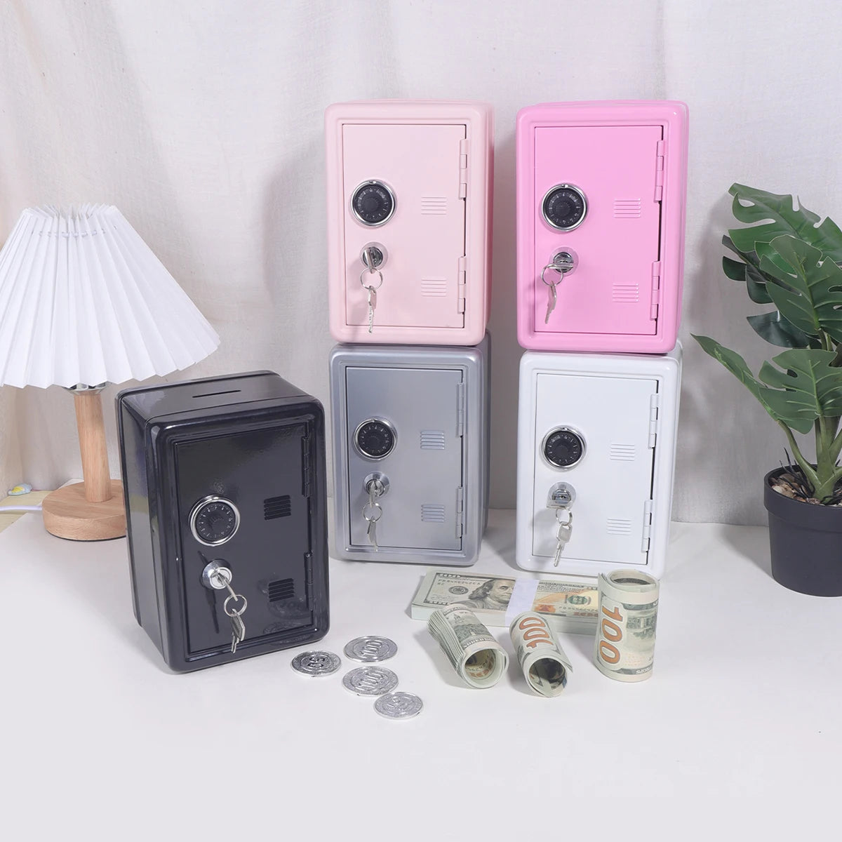 Three pink and silver vintage metal piggy banks with combination locks and keys displayed on a white surface.