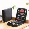 A black portable sewing kit with various tools is displayed on a wooden surface.