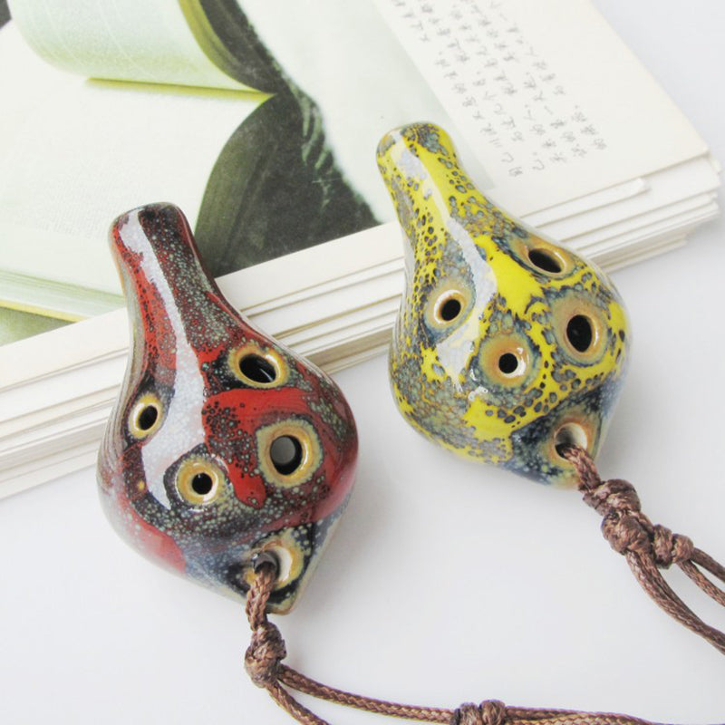 Handcrafted ceramic pendant ocarina with six holes featuring mottled yellow and red glaze.
