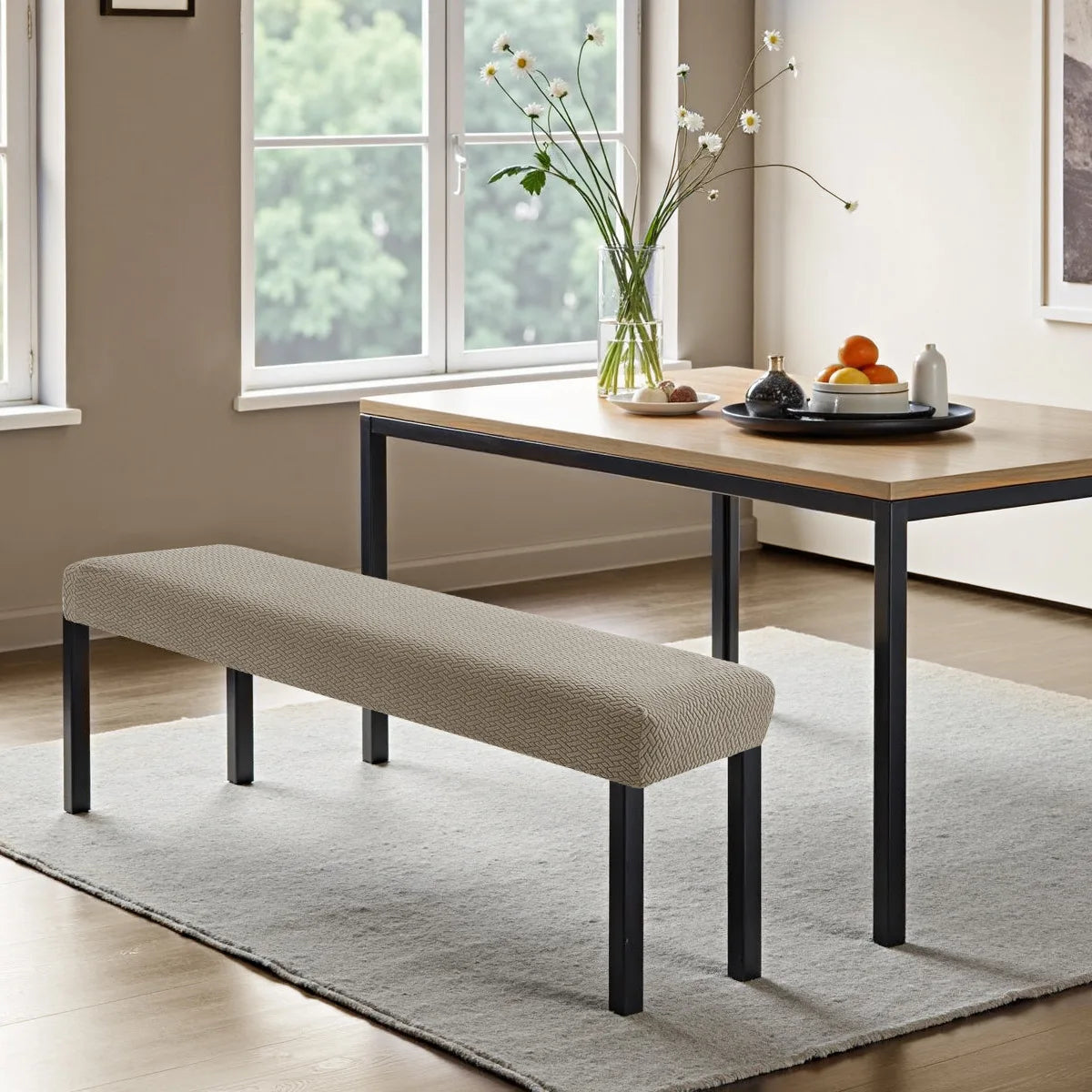 A light beige stretch jacquard bench cover placed on a modern wooden table in a bright room.