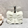 A white ceramic pump dispenser with a silver pump mechanism sits on a gray surface.