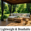 A light-colored outdoor living area featuring a wicker sofa and wooden deck surrounded by lush greenery.