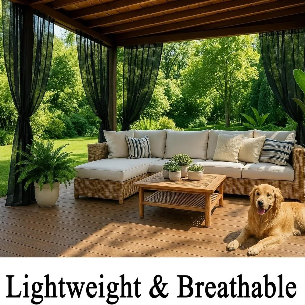 A light-colored outdoor living area featuring a wicker sofa and wooden deck surrounded by lush greenery.